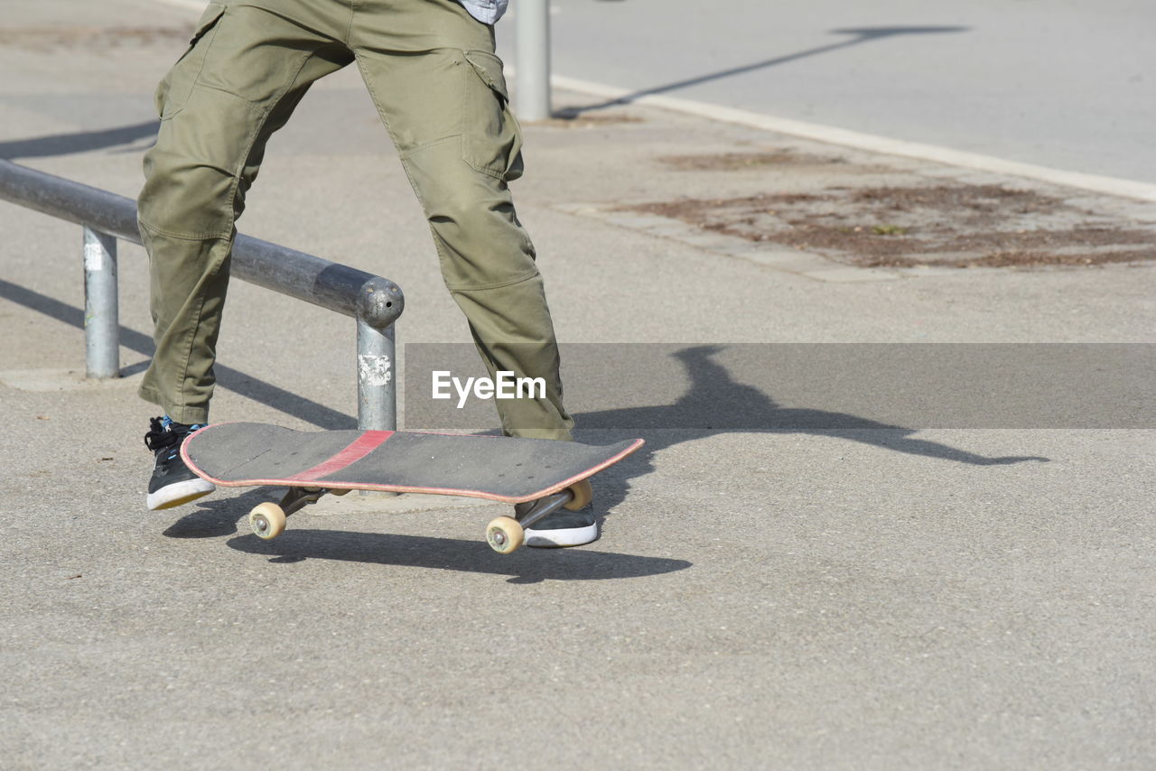 Low section of man skateboarding on road