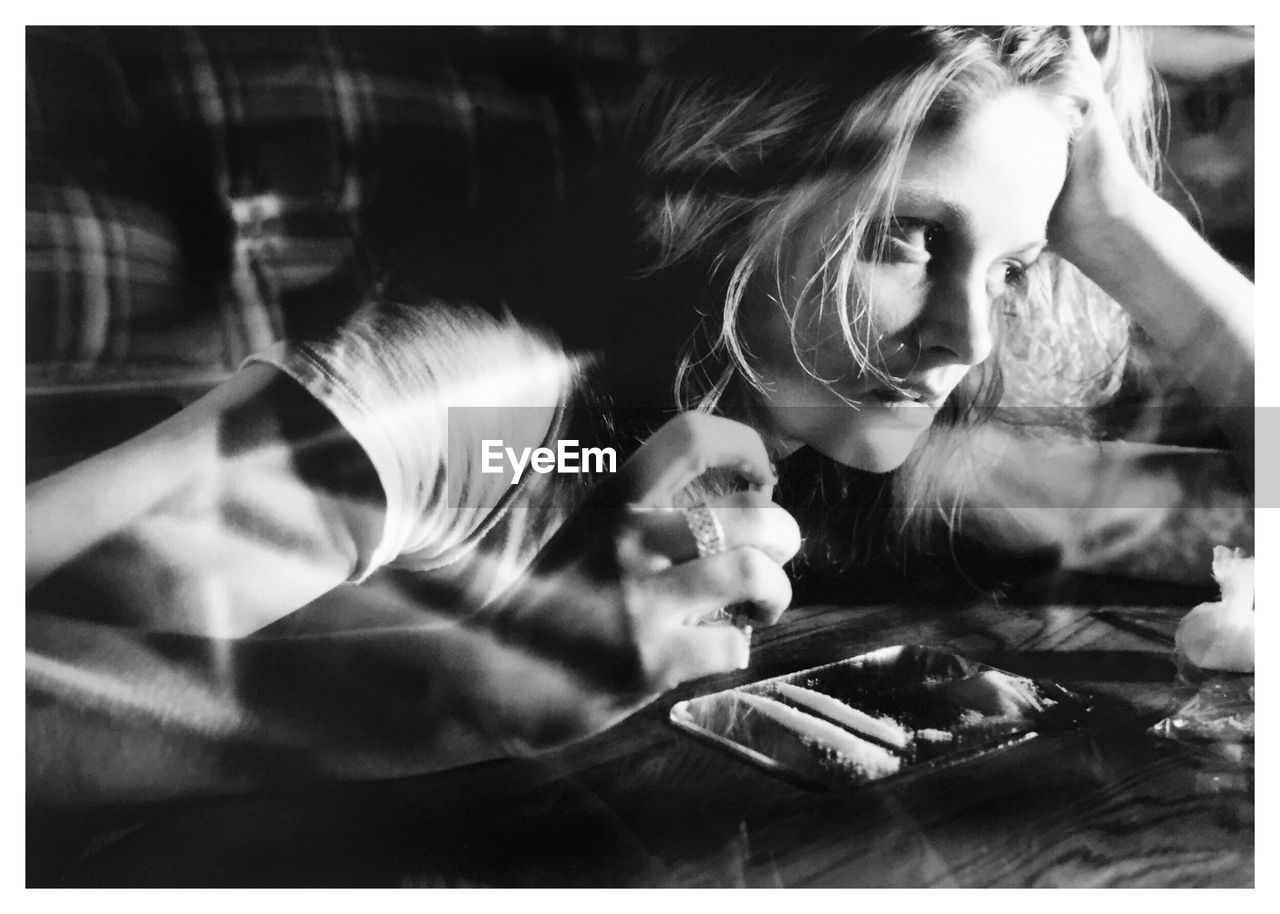 Thoughtful woman looking away by cocaine on coffee table