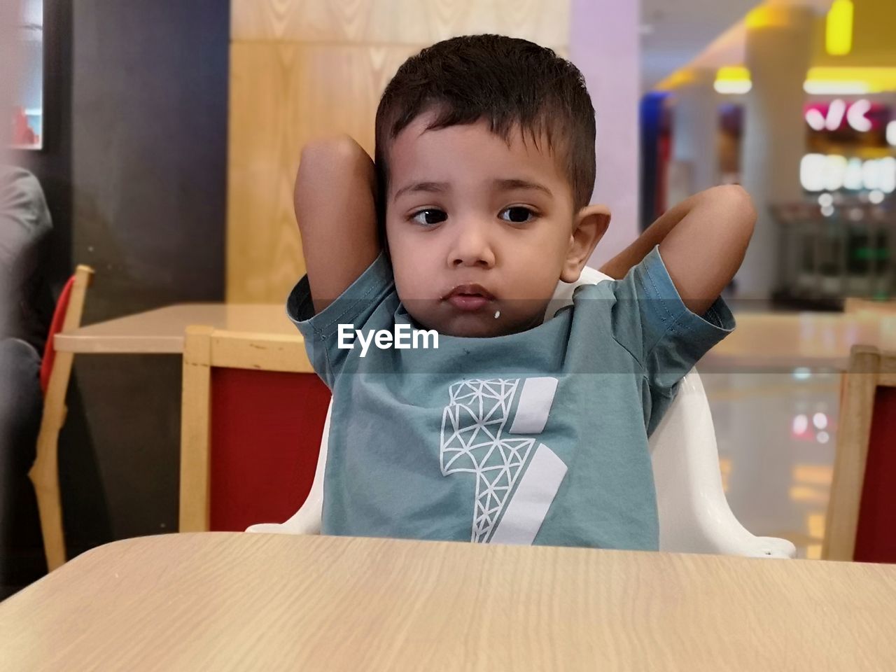 Portrait of cute boy sitting at table in restaurant