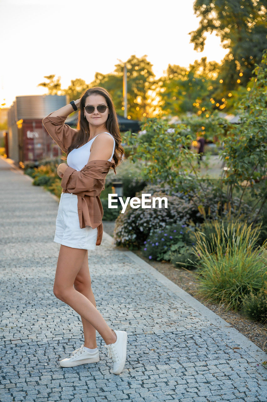 full length of young woman standing against trees