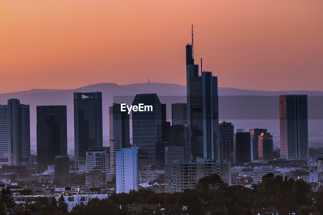 Skyscrapers in city at sunset