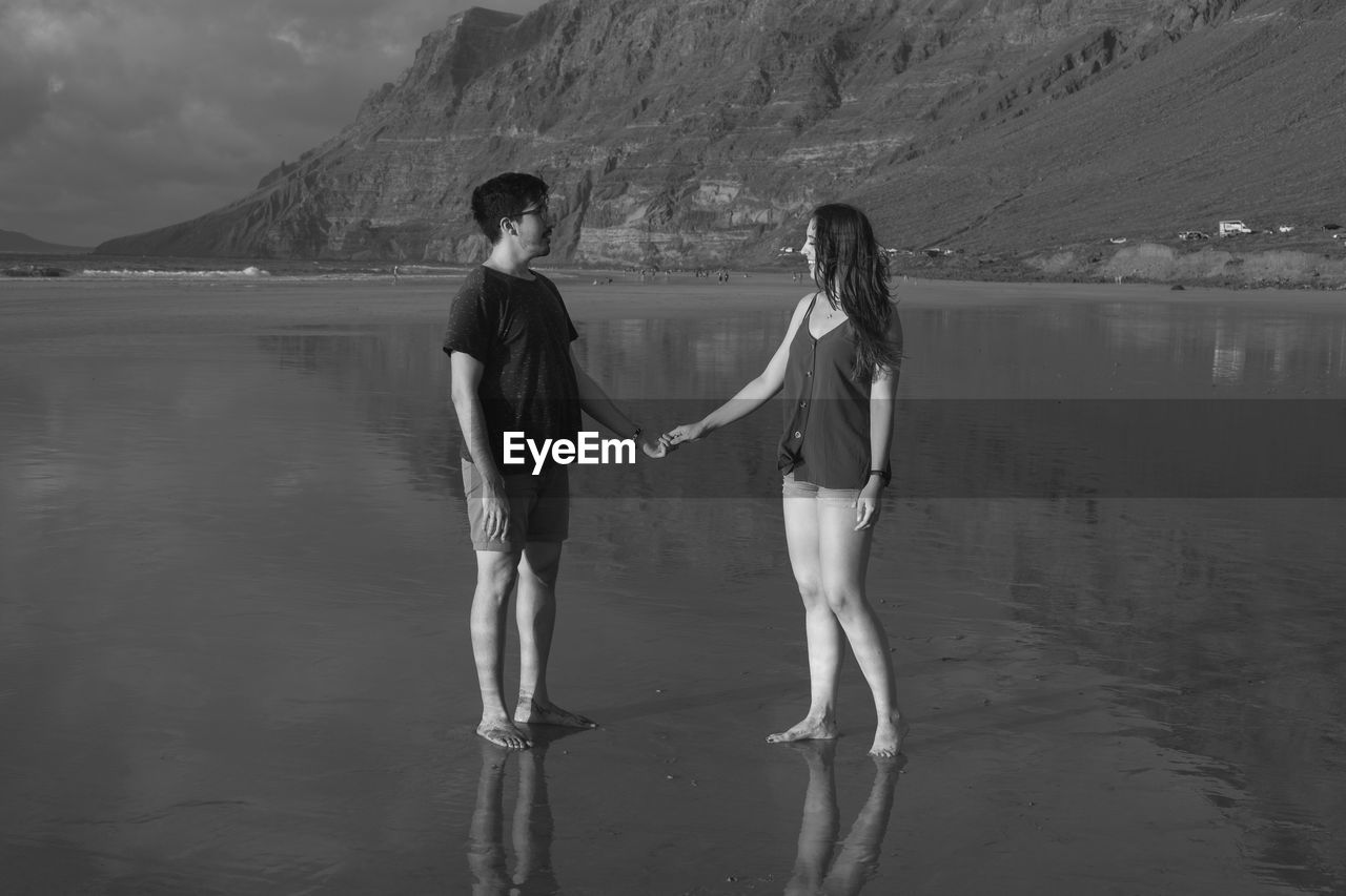 Couple standing on beach against mountain