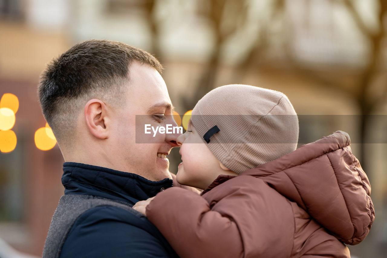 A happy father and three year old son hug in a city street. warm relationships between parents 