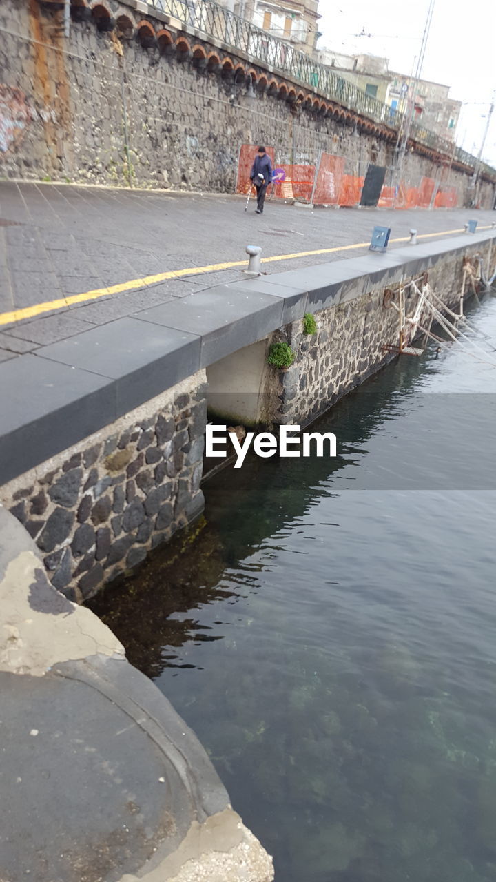 PEOPLE IN BRIDGE OVER CANAL