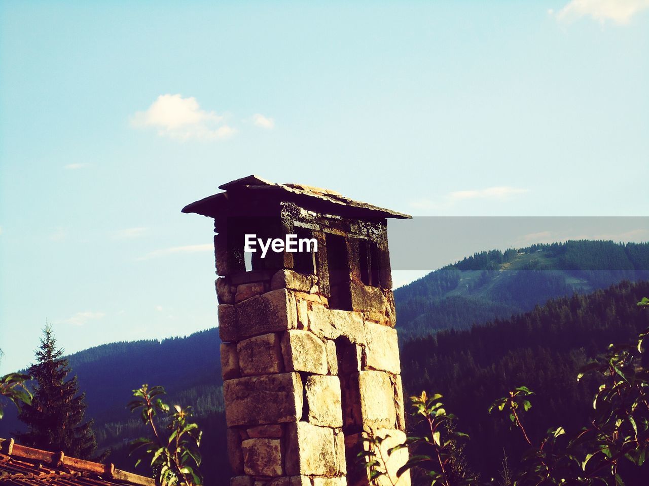 LOW ANGLE VIEW OF CLOCK TOWER AGAINST MOUNTAIN