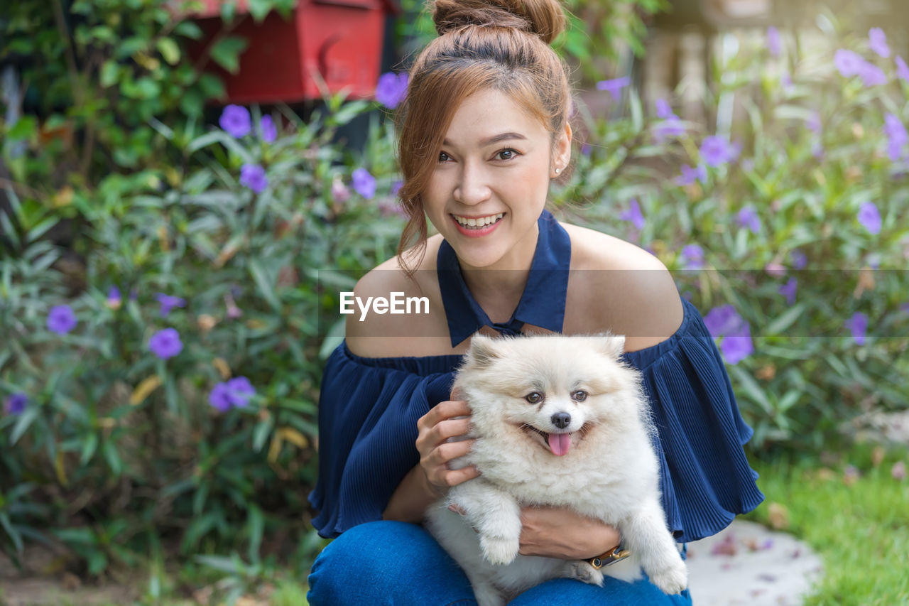 Portrait of smiling young woman with dog outdoors