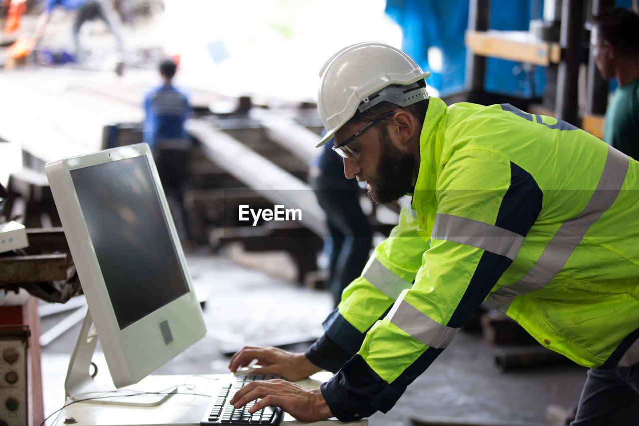 Side view of engineer using computer in factory