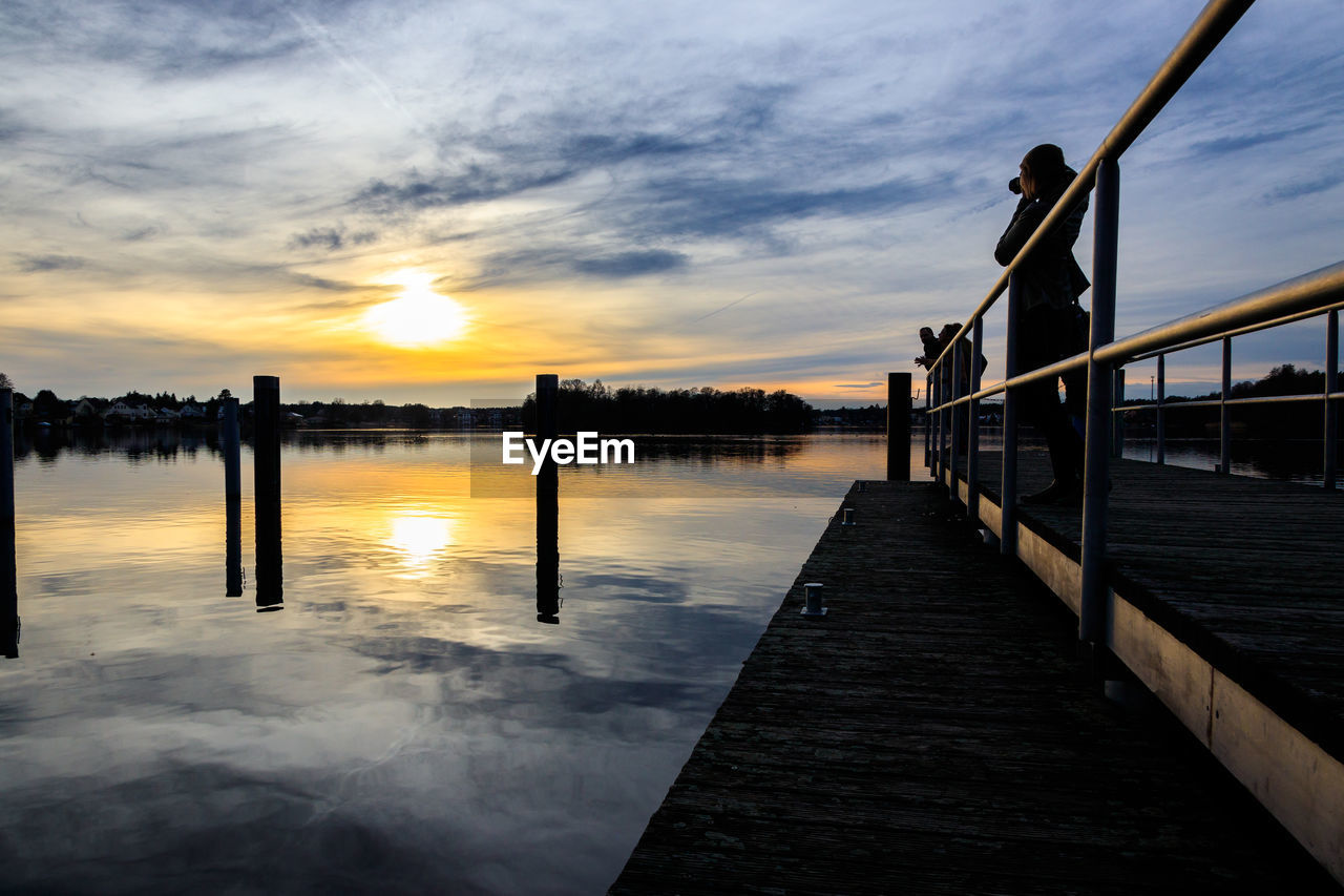 PIER OVER LAKE AGAINST ORANGE SKY