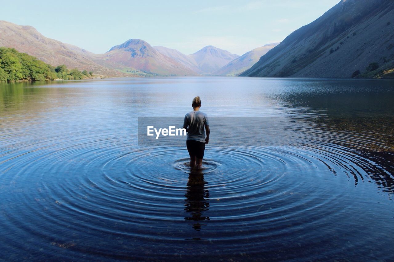 Scenic rear view of young woman walking in lake