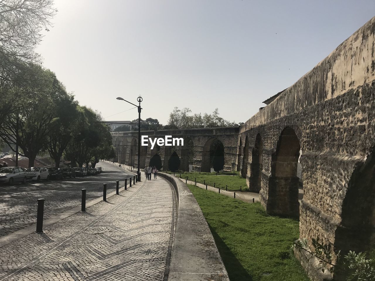 Empty footpath by buildings against clear sky