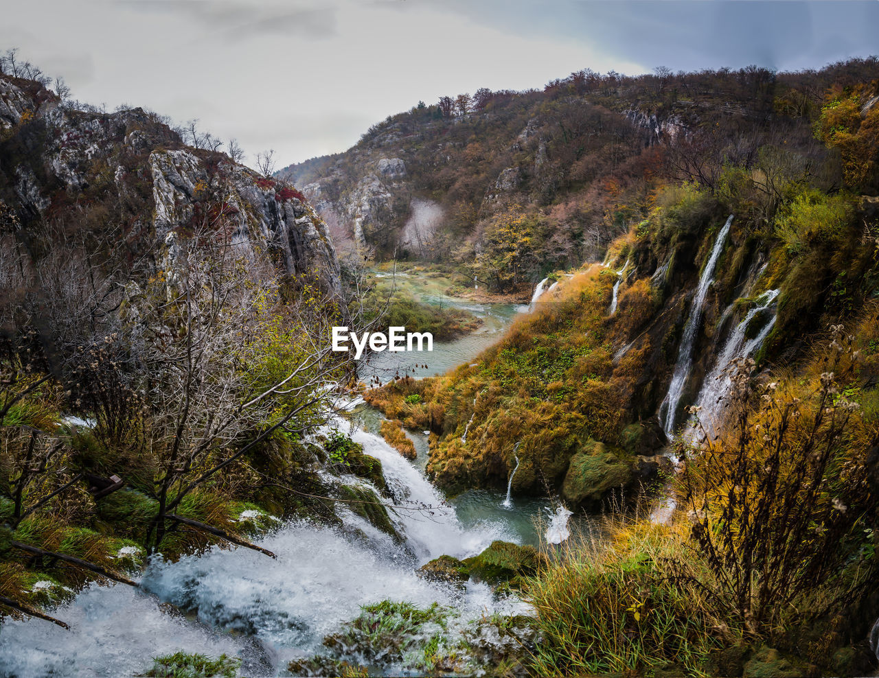 High angle view of stream flowing amidst mountain against sky