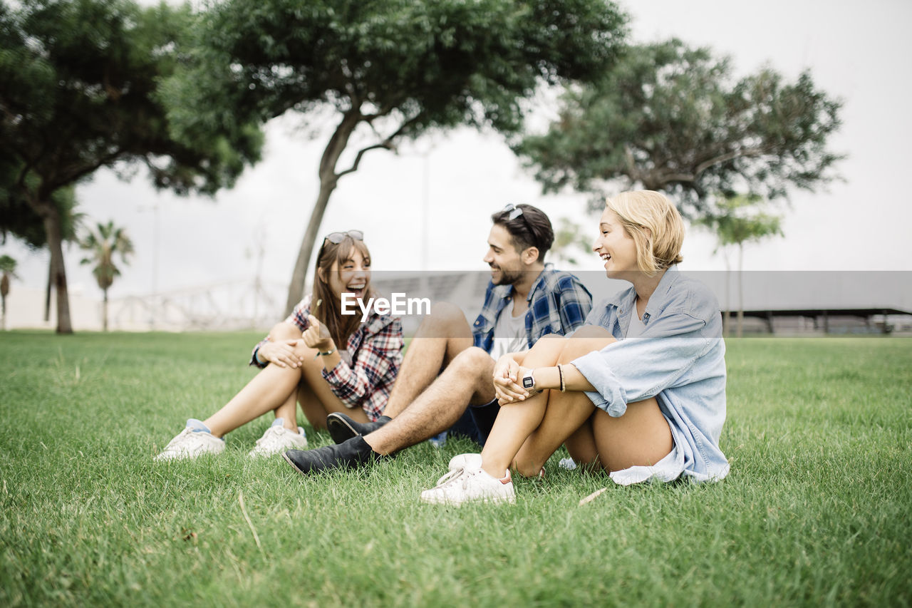 Happy friends sitting on grassy field