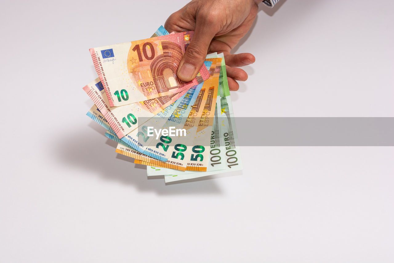 CLOSE-UP OF A HAND HOLDING PAPER OVER WHITE BACKGROUND