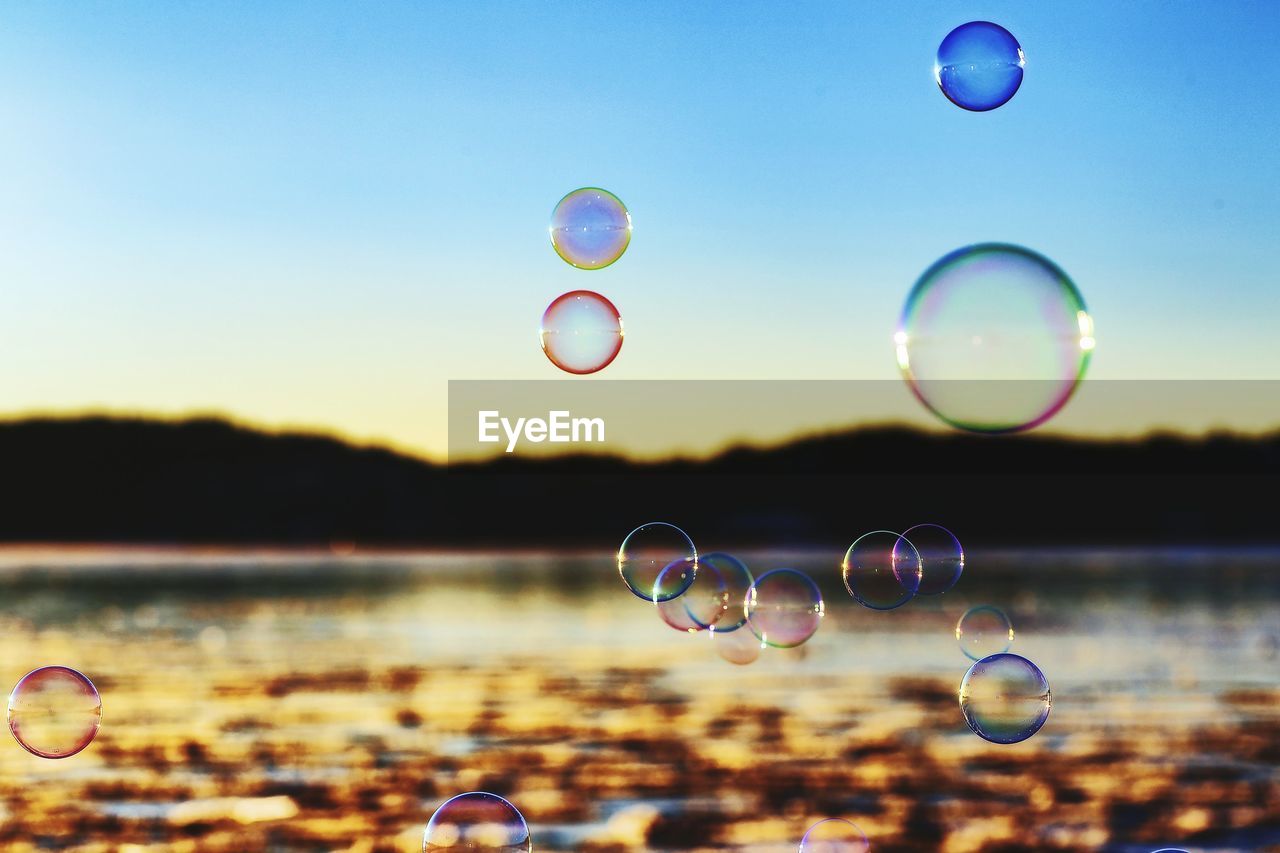 Close-up of bubbles over river against sky