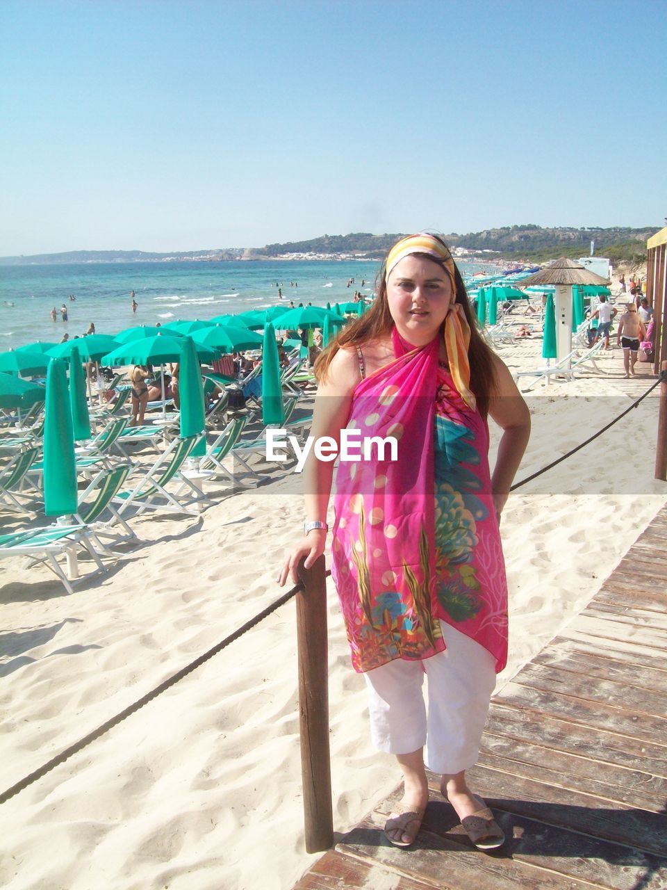 BEAUTIFUL YOUNG WOMAN ON BEACH AGAINST SKY