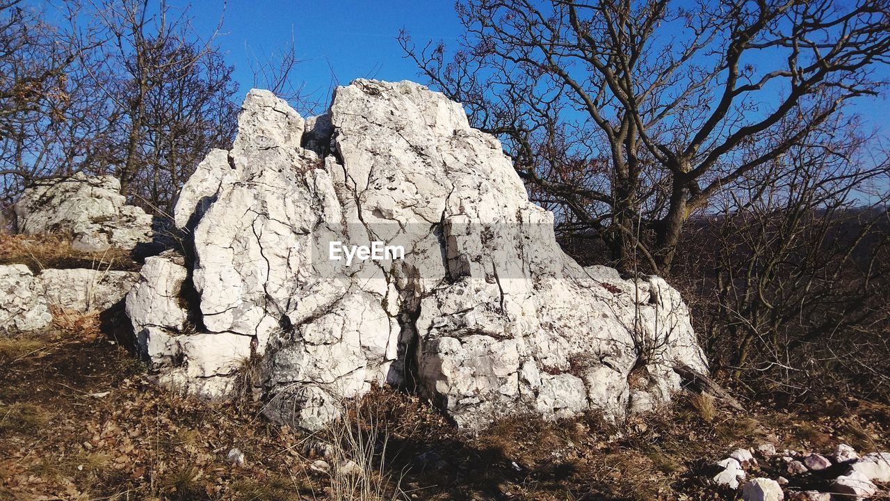 LOW ANGLE VIEW OF ROCK FORMATION ON FIELD AGAINST SKY