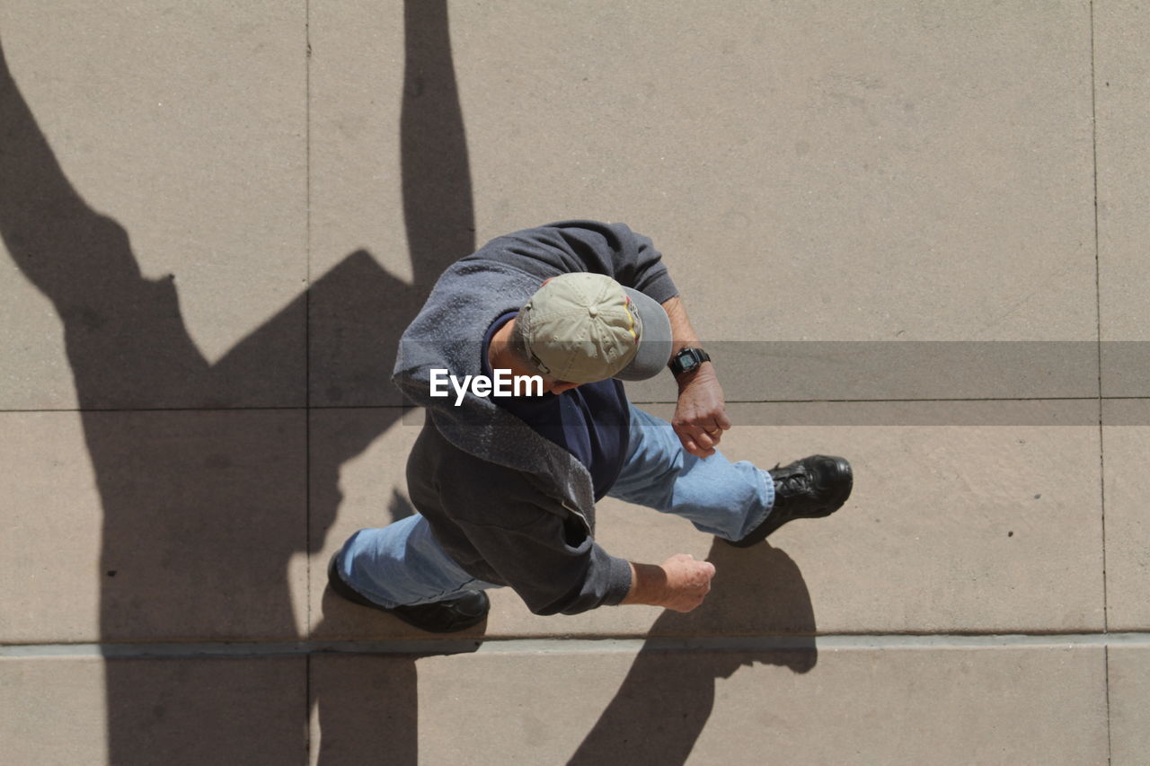 High angle view of man checking time while walking on footpath