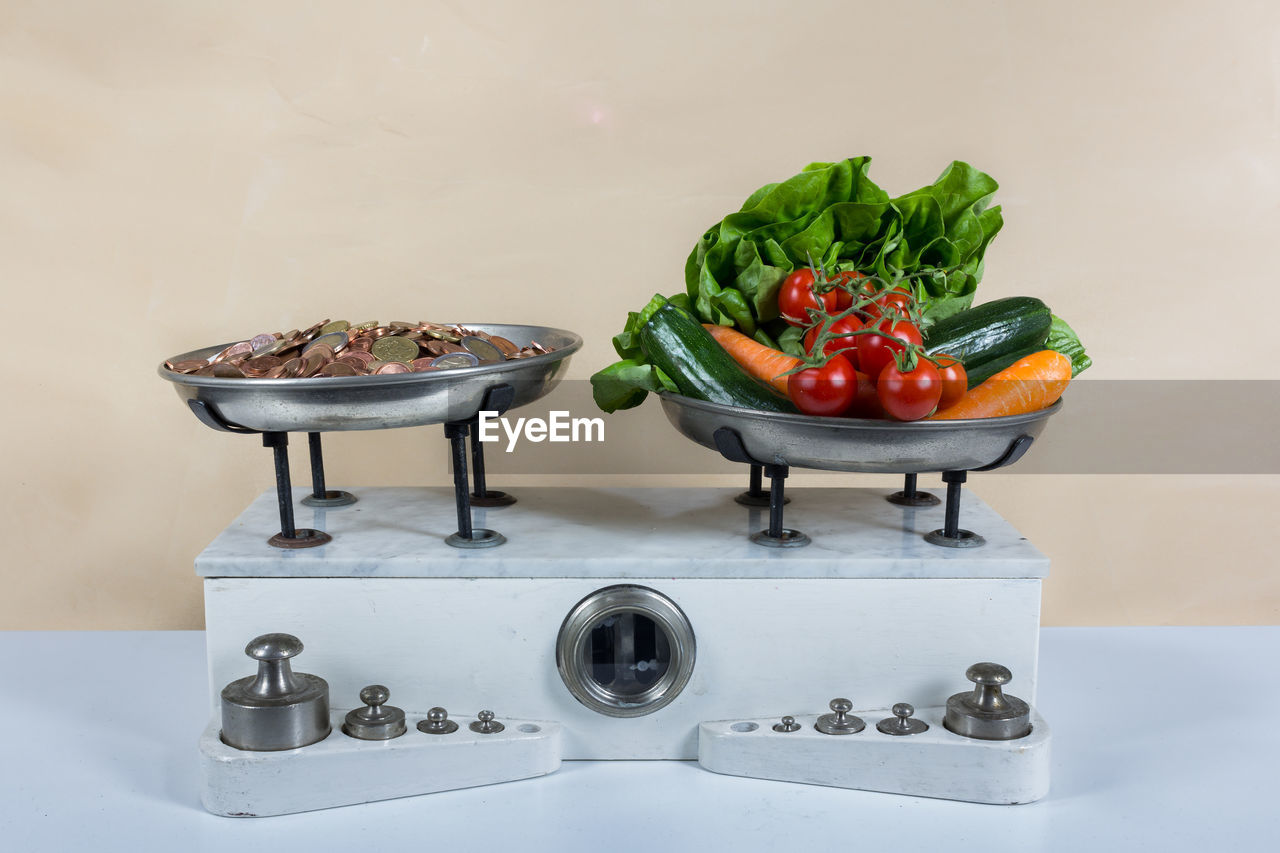Close-up of coins and various vegetables on weight scale