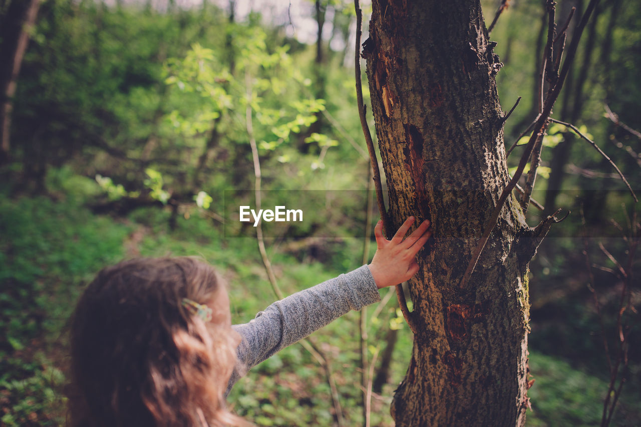 Girl touching tree trunk in forest