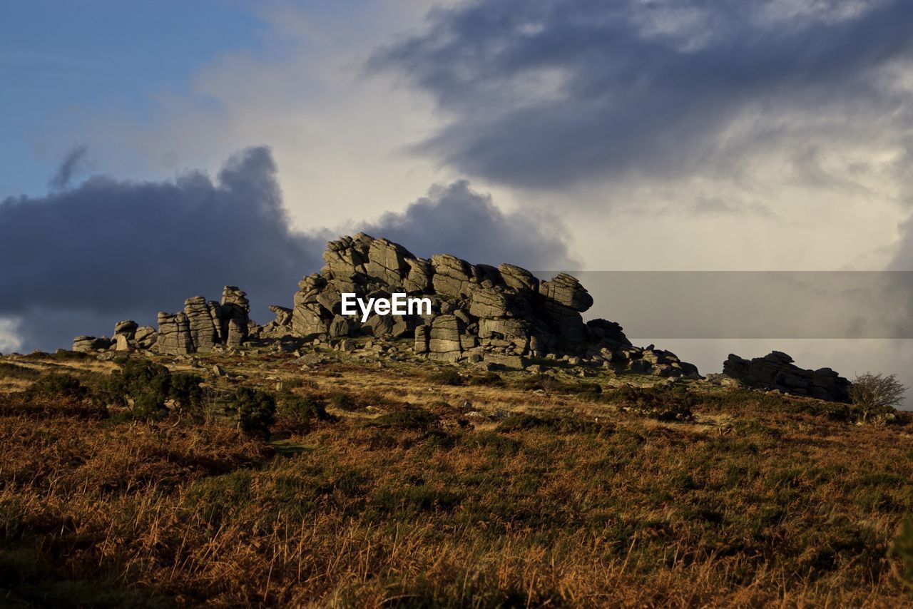 Rock formation on hill against sky