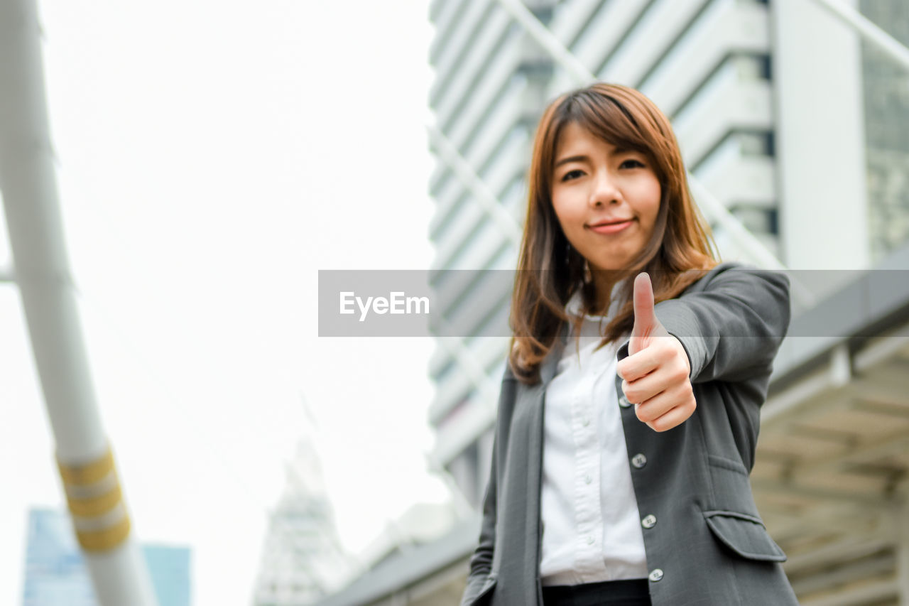 Young businesswoman gesturing while standing in city