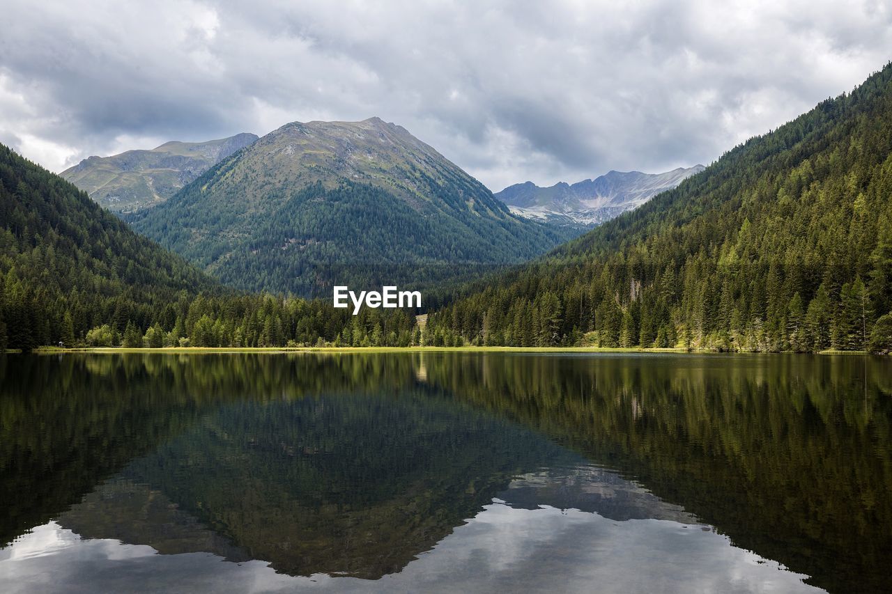 water, mountain, scenics - nature, reflection, lake, beauty in nature, nature, tree, environment, forest, landscape, mountain range, cloud, sky, wilderness, plant, tranquility, tranquil scene, land, pine tree, coniferous tree, pine woodland, pinaceae, no people, travel destinations, highland, non-urban scene, body of water, idyllic, reservoir, travel, woodland, tourism, activity, reflection lake, outdoors, mountain peak, overcast, holiday, leisure activity, summer, snow, trip, vacation, valley, day, panoramic, remote