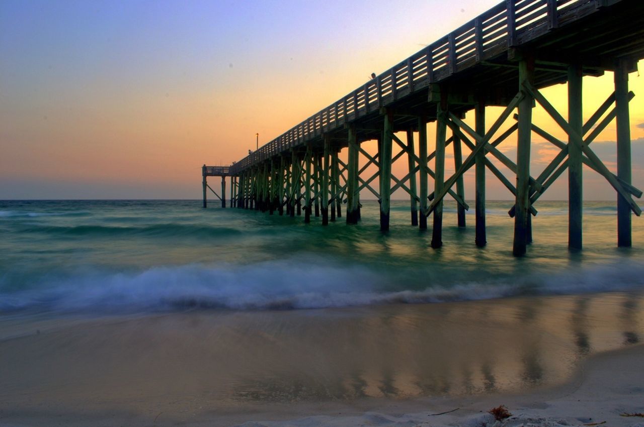 Pier in sea at sunset