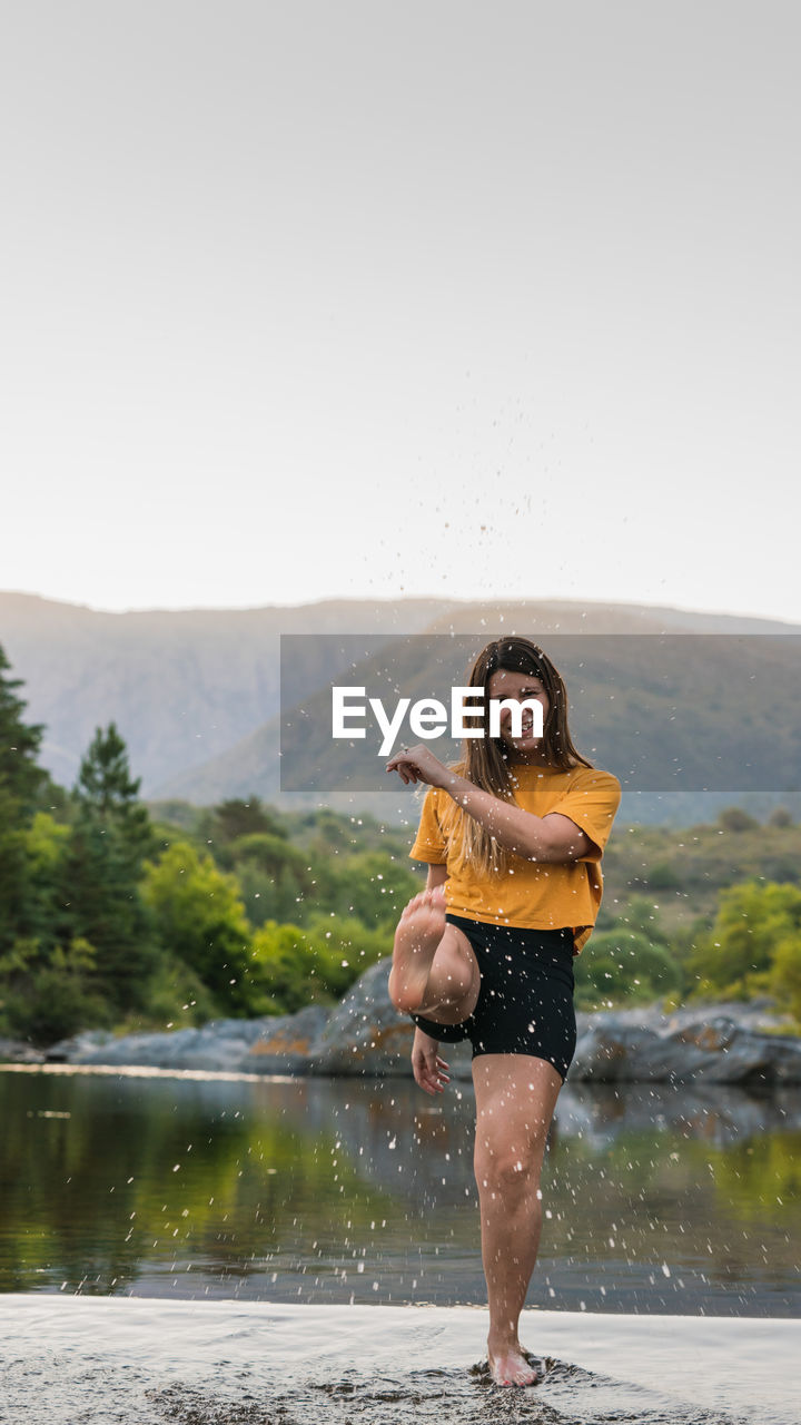 Full length of woman standing by lake against sky