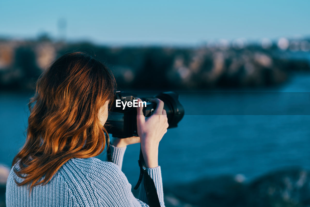 REAR VIEW PORTRAIT OF WOMAN PHOTOGRAPHING SEA