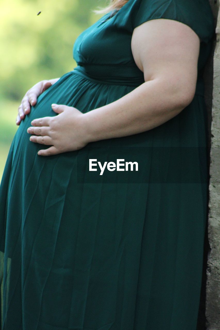 Midsection of pregnant woman standing outdoors