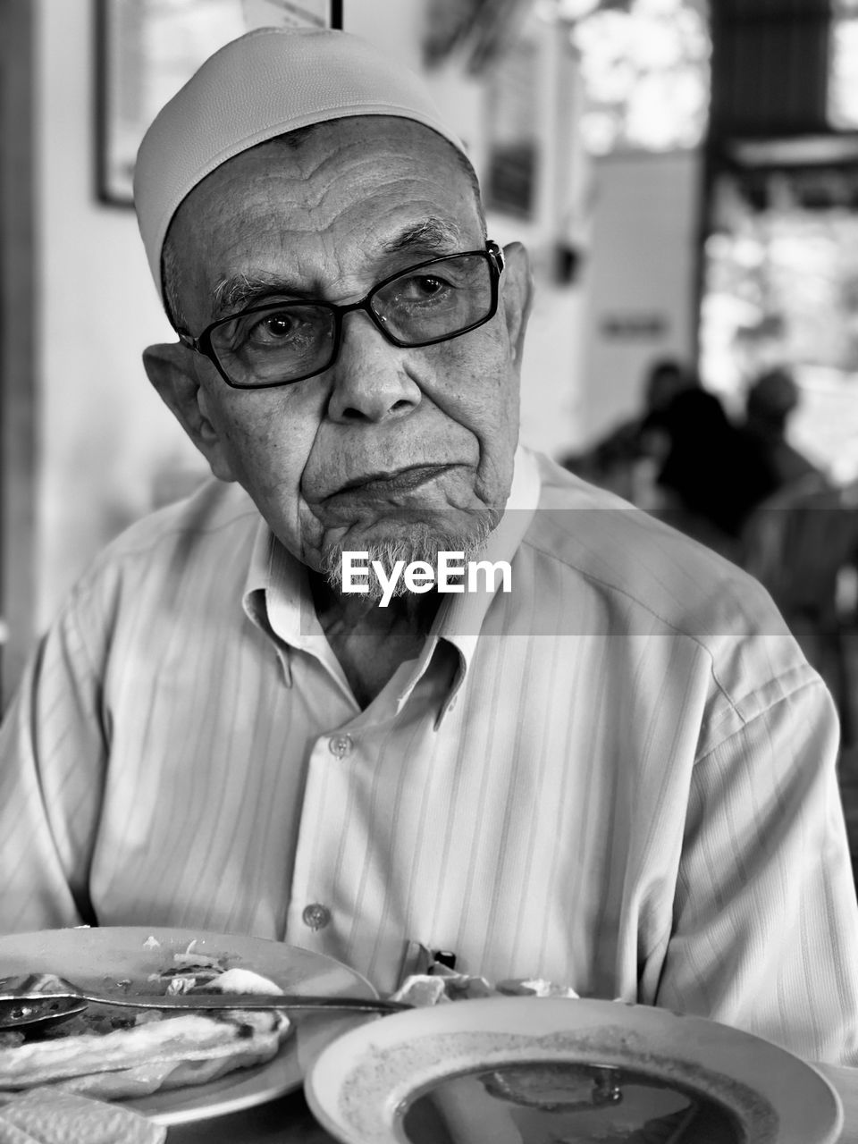 Senior man looking away while sitting in restaurant