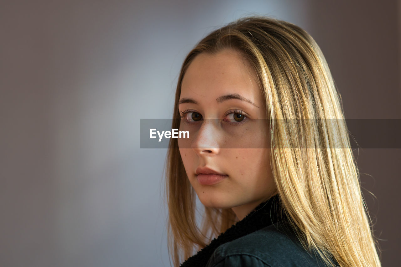 Portrait of a pretty teenage girl with long natural blond hair and smooth skin looking at camera