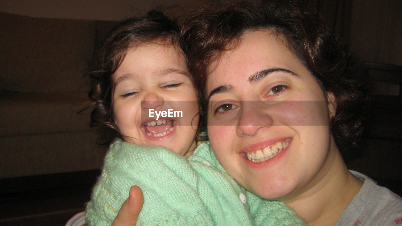 Portrait of smiling mother with daughter at home