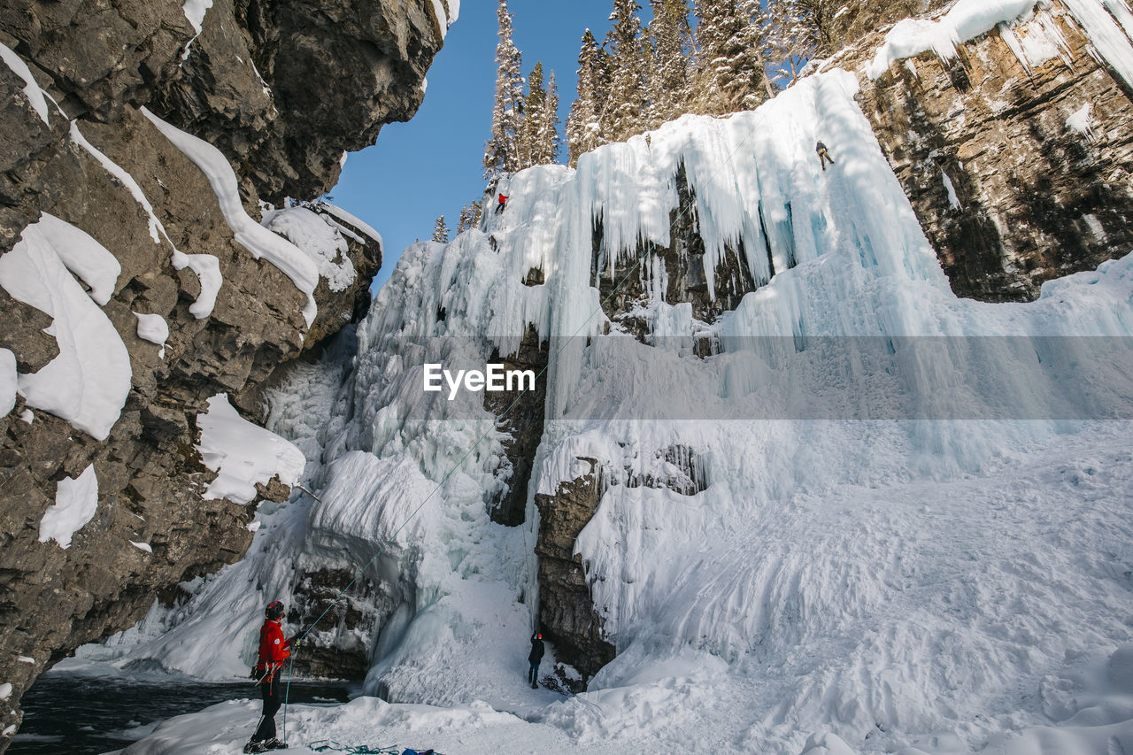 Side view of man with rope standing on snowcapped mountain