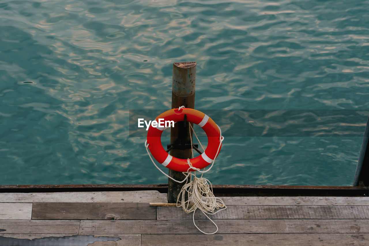 High angle view of a lifebelt hanging on a wooden post at the railing