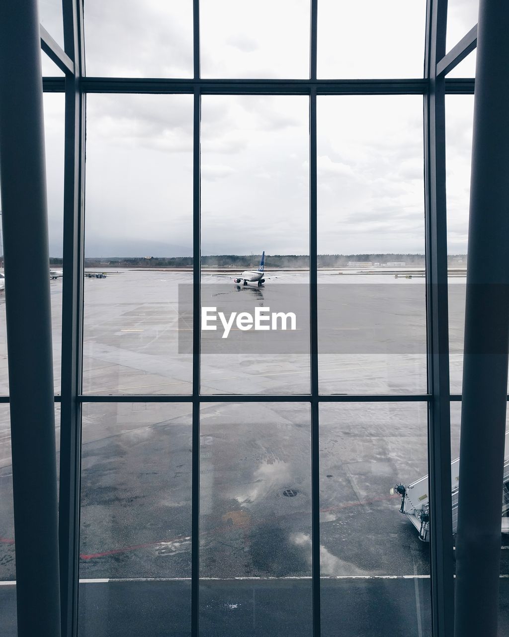 Airplane on airport runway seen through glass window