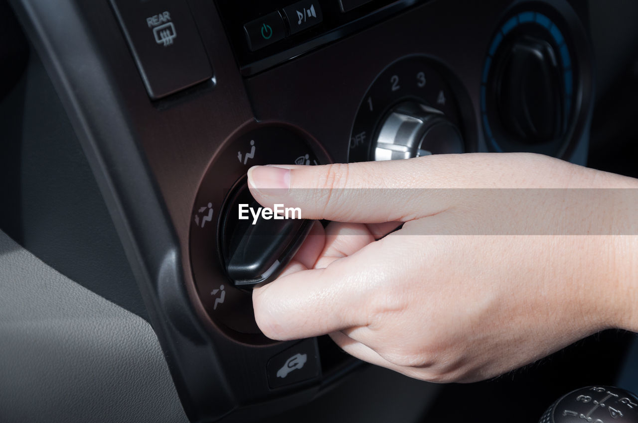 Cropped hand of woman holding knob in car