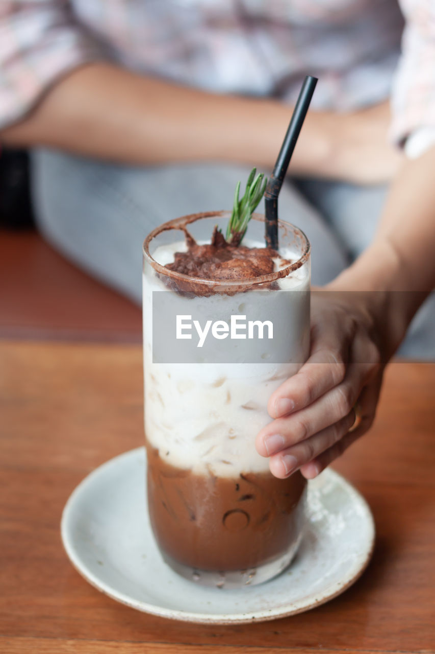 Midsection of person holding drink on table