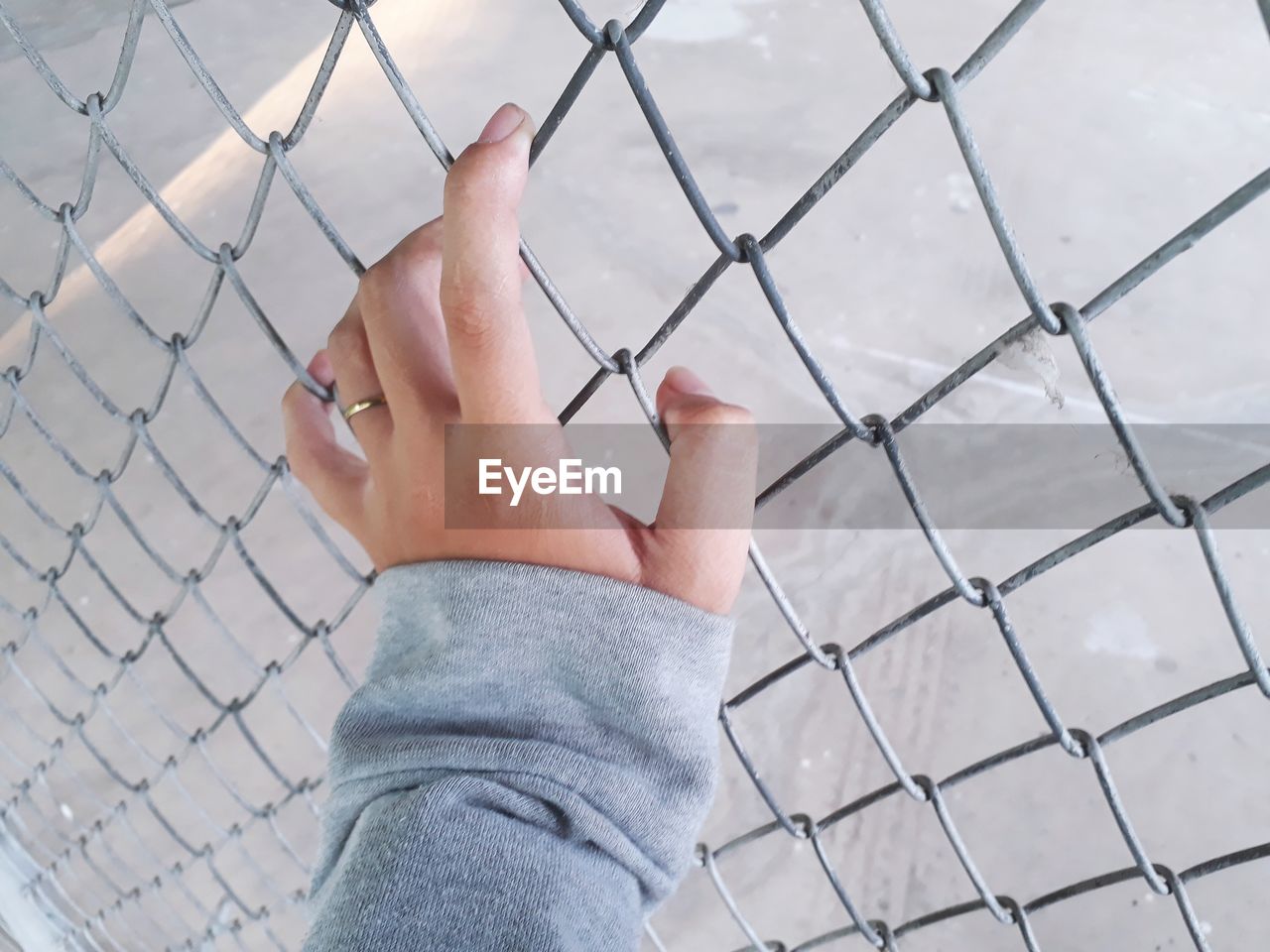 Cropped hand of woman holding chainlink fence