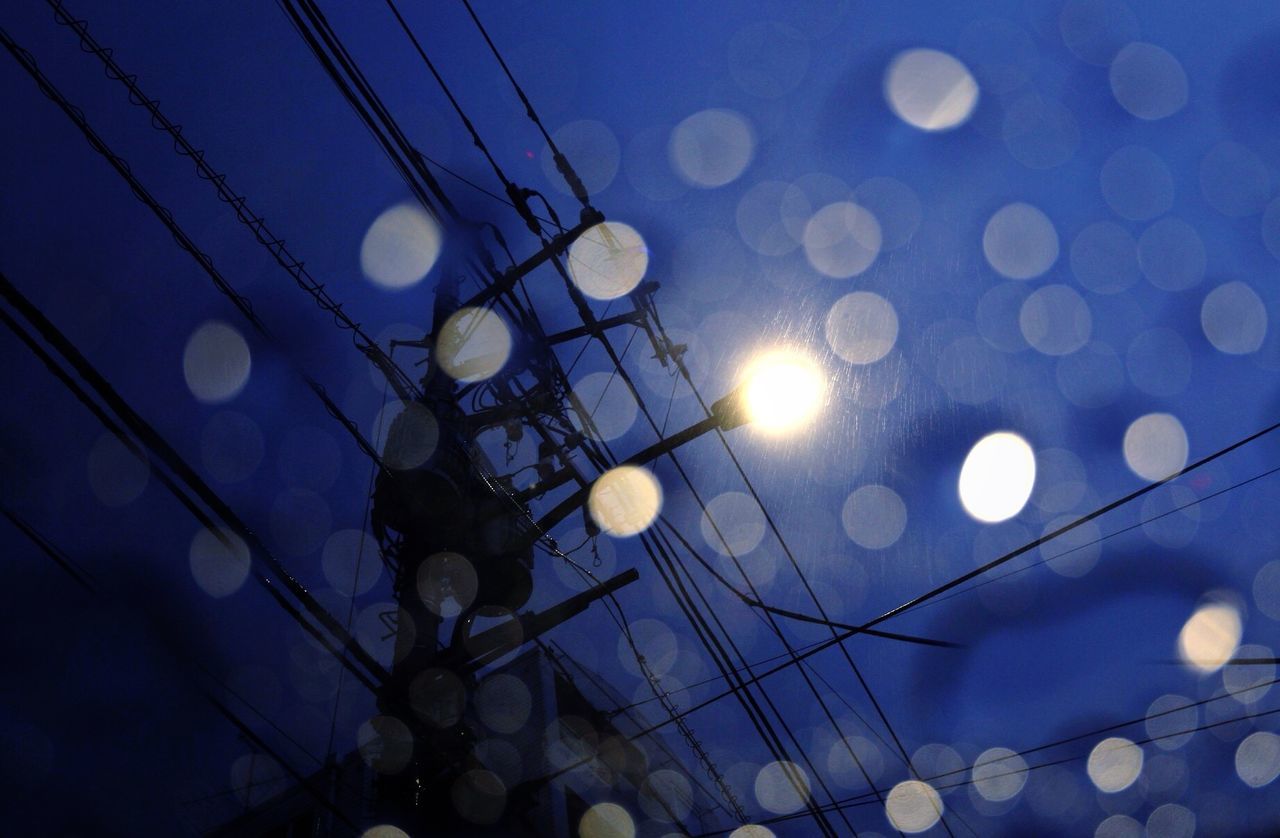 LOW ANGLE VIEW OF ILLUMINATED LIGHT BULB AGAINST BLUE SKY