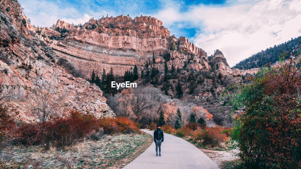 REAR VIEW OF PERSON ON MOUNTAIN AGAINST SKY