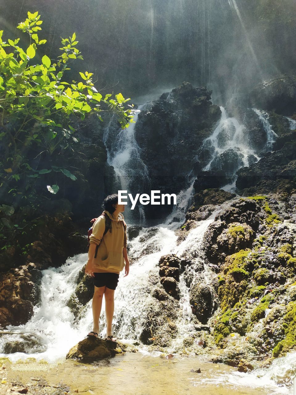 Full length of girl standing on rock against waterfall