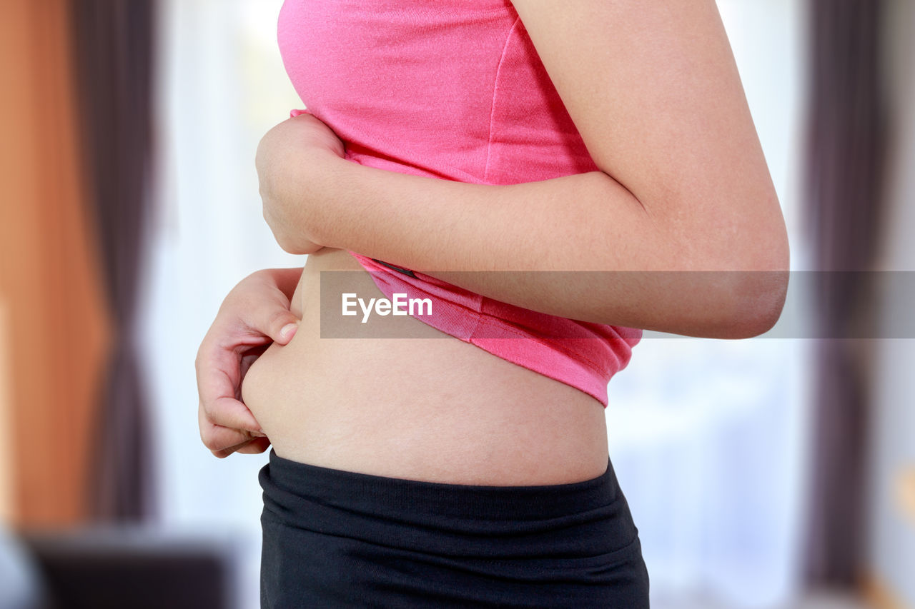 Midsection of woman holding tummy