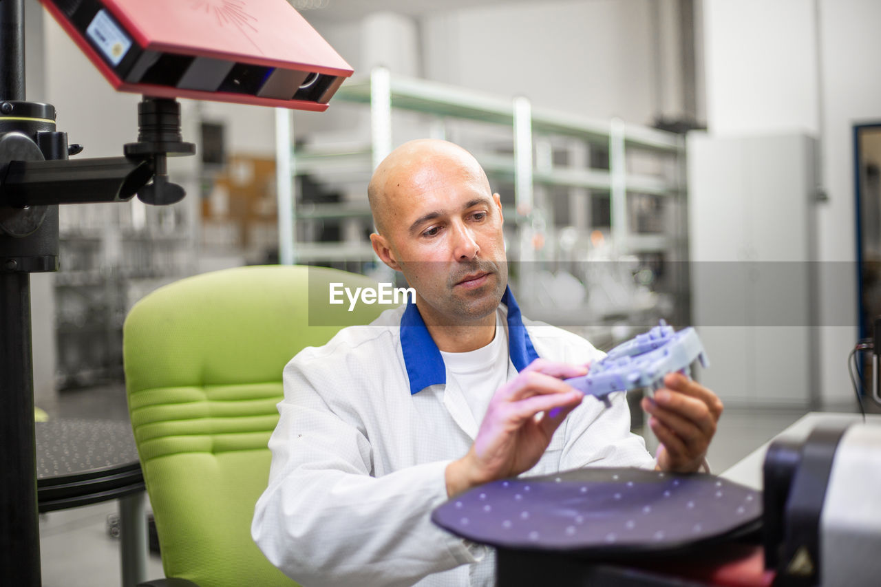 PORTRAIT OF MAN WORKING IN OFFICE SITTING