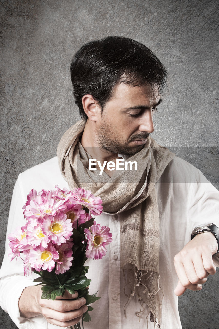 CLOSE-UP PORTRAIT OF A MAN HOLDING FLOWER