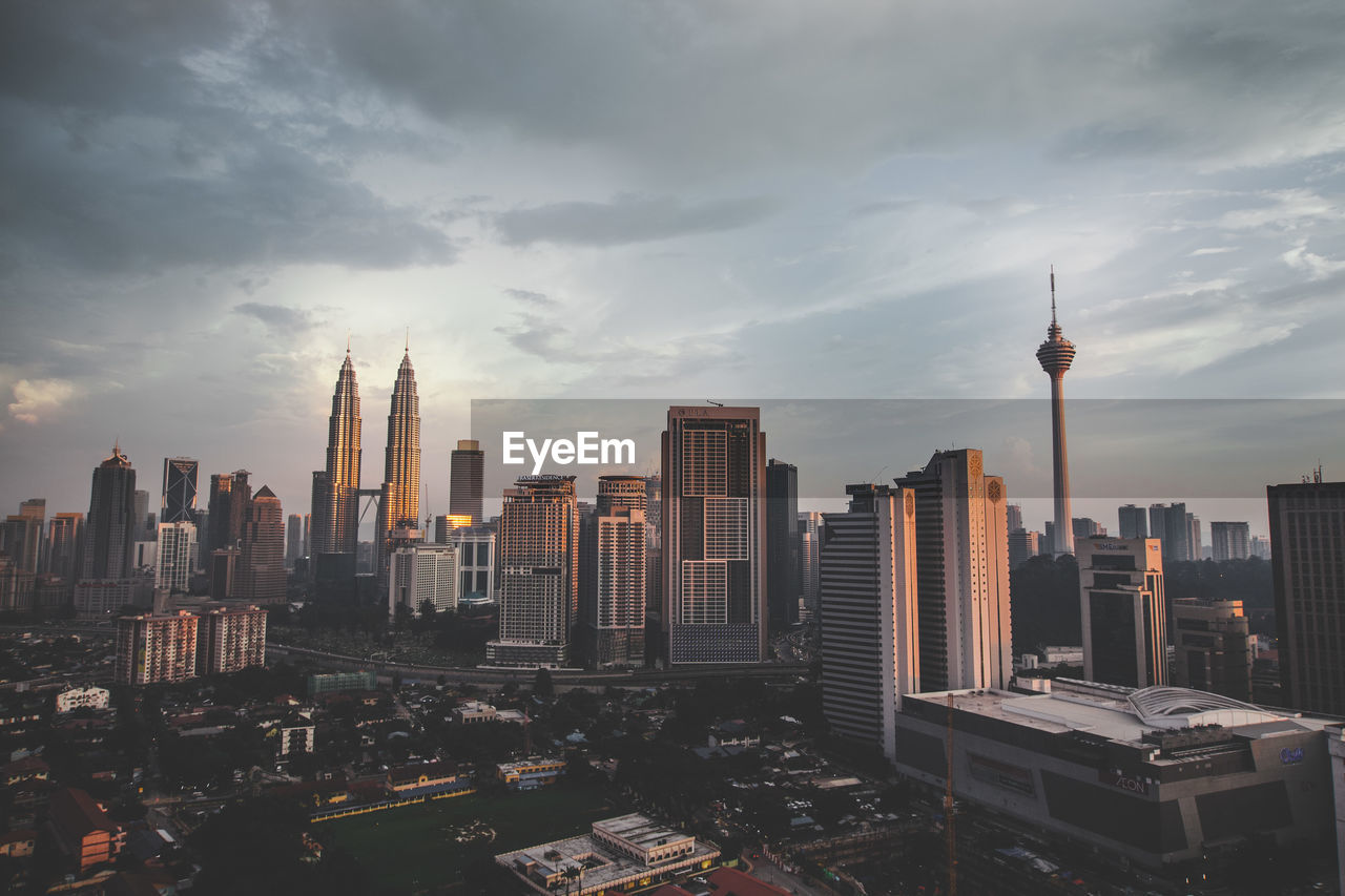 Kuala lumpur tower and petronas towers in city against sky during sunset