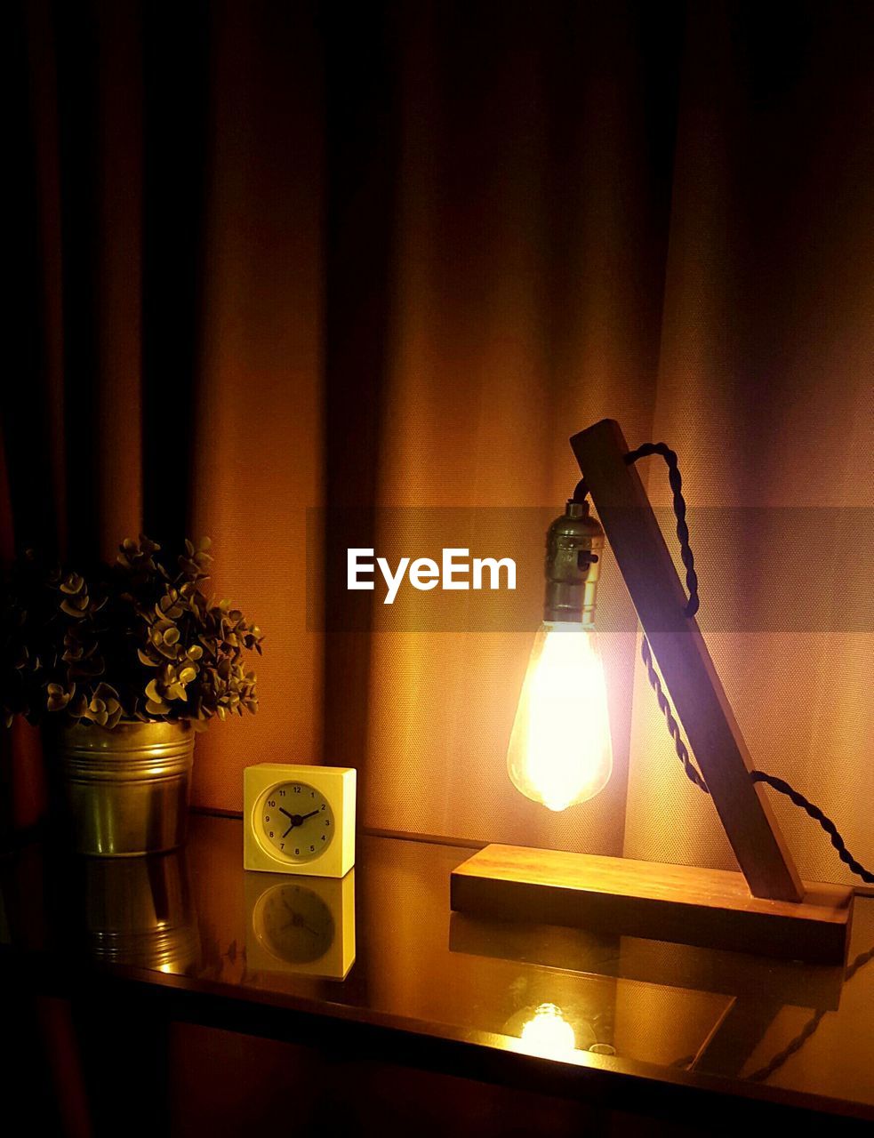 High angle view of alarm clock on table against curtain in room