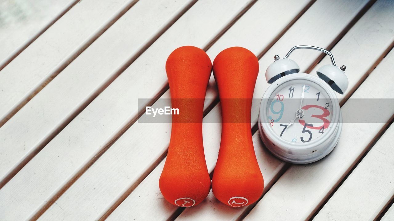 Alarm clock and dumbbells on table