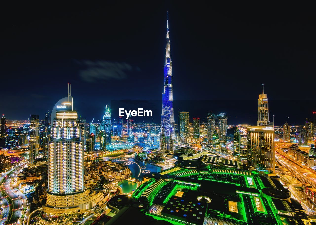 AERIAL VIEW OF ILLUMINATED BUILDINGS IN CITY AT NIGHT