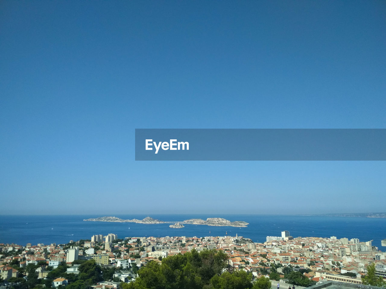 Aerial view of townscape by sea against clear blue sky